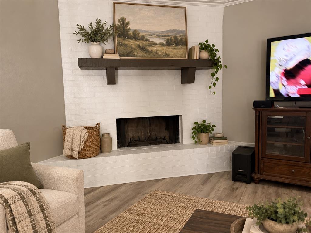 Corner fireplace featuring white-painted brick and a dark wood-finish mantel