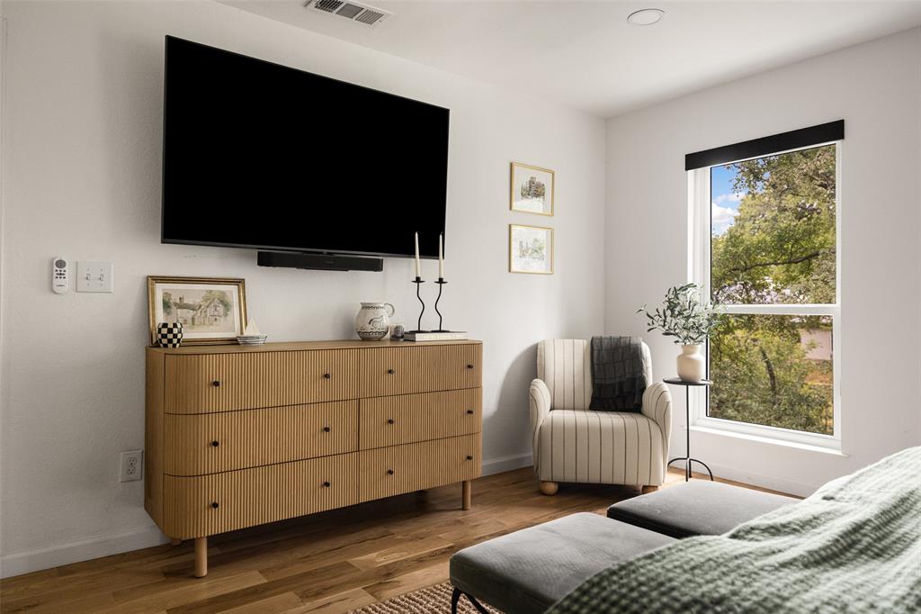 Recessed lighting, wood-finish flooring, and a large window with roller shades