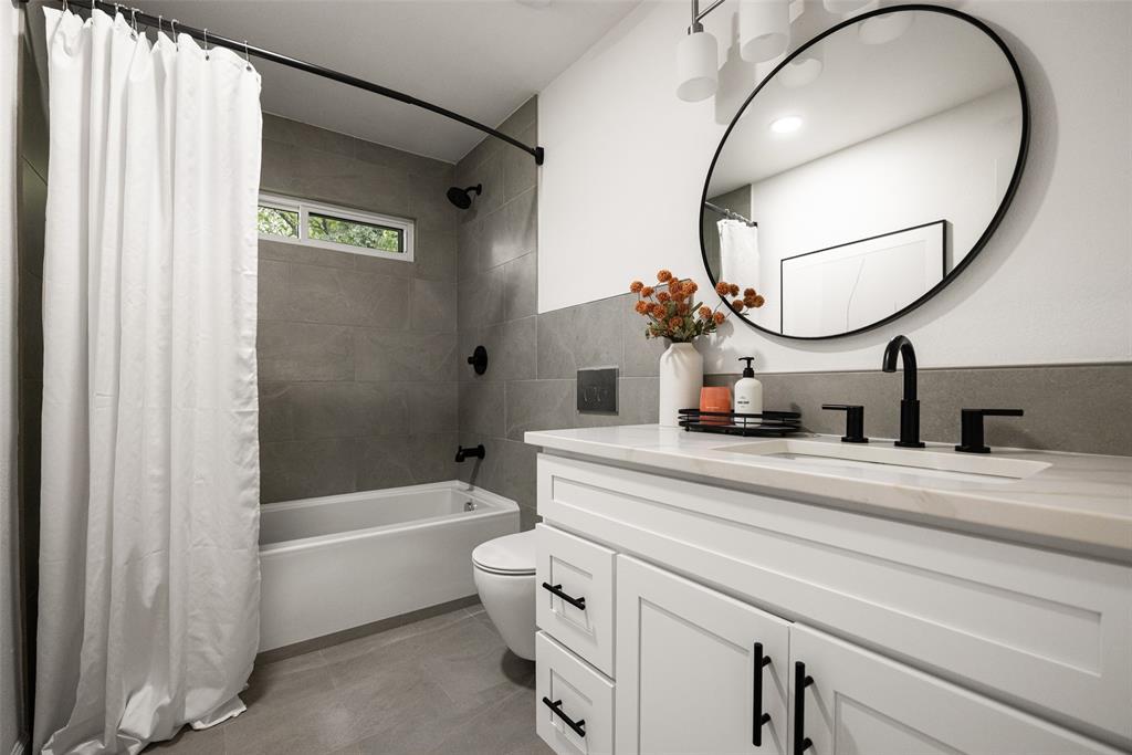 Bathroom featuring a white vanity with shaker-style cabinetry, matte black hardware, a rectangular undermount sink, and a light-toned countertop