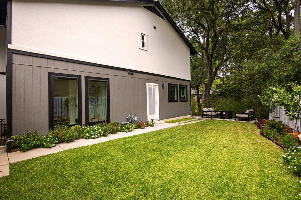 Backyard featuring a lush lawn, established trees, stepping stone pathway, and mature landscaping