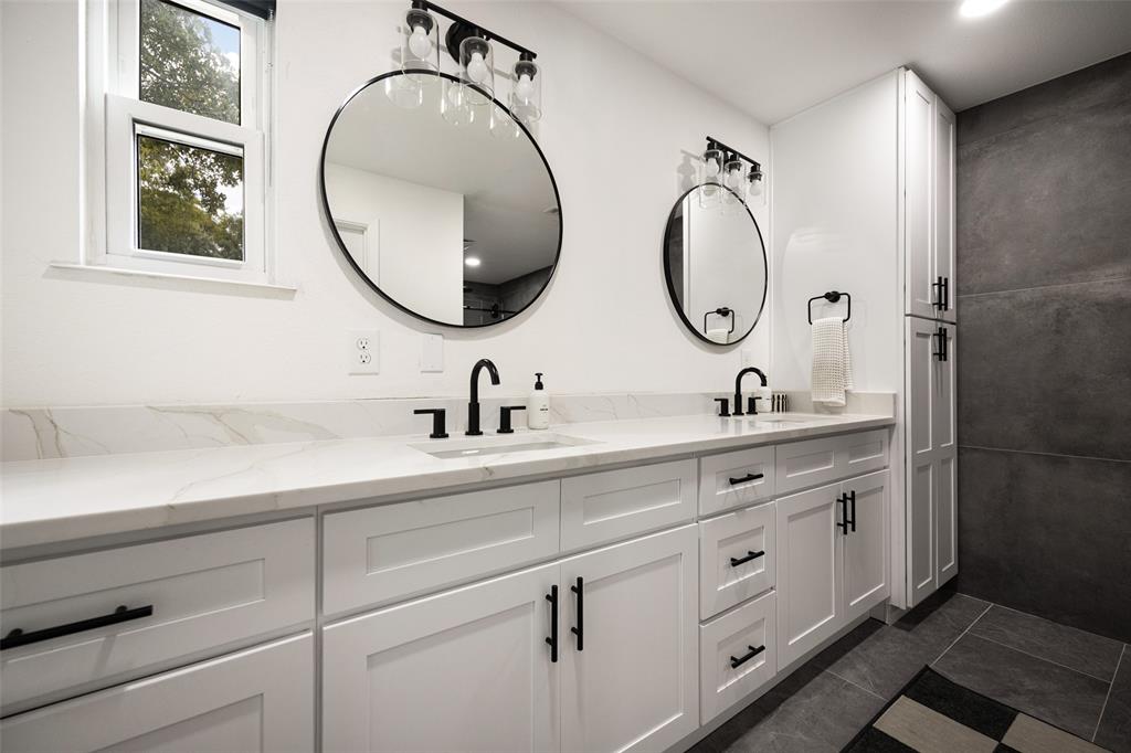 Dual vanity with white cabinetry, matte black hardware, and stone-finish countertops