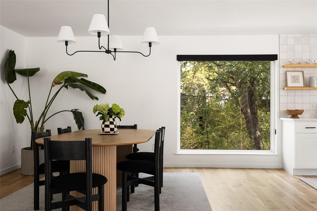 Wood-finish flooring, white walls, and a large window with roller shade