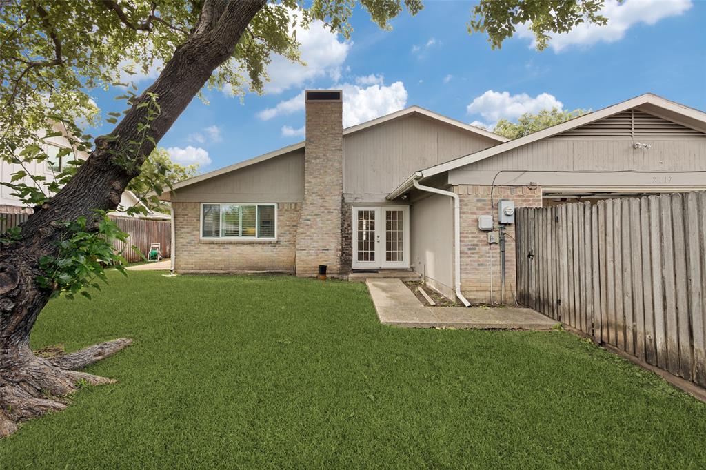 Large fenced backyard with shade tree and sprinkler system.