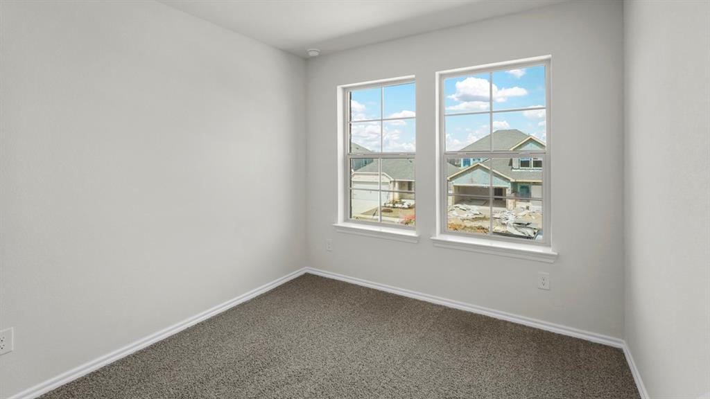 Room featuring neutral wall paint, gray textured carpeting, and two large grid-pattern windows with white trim
