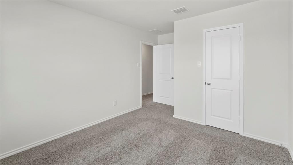 Neutral-toned wall, two-panel interior doors, gray carpet flooring, baseboard trim, and ceiling ventilation