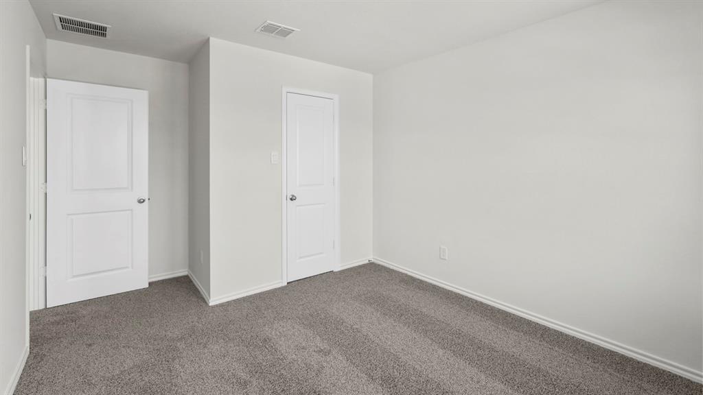 Neutral-toned room featuring light gray walls, plush gray carpeting, and white baseboards