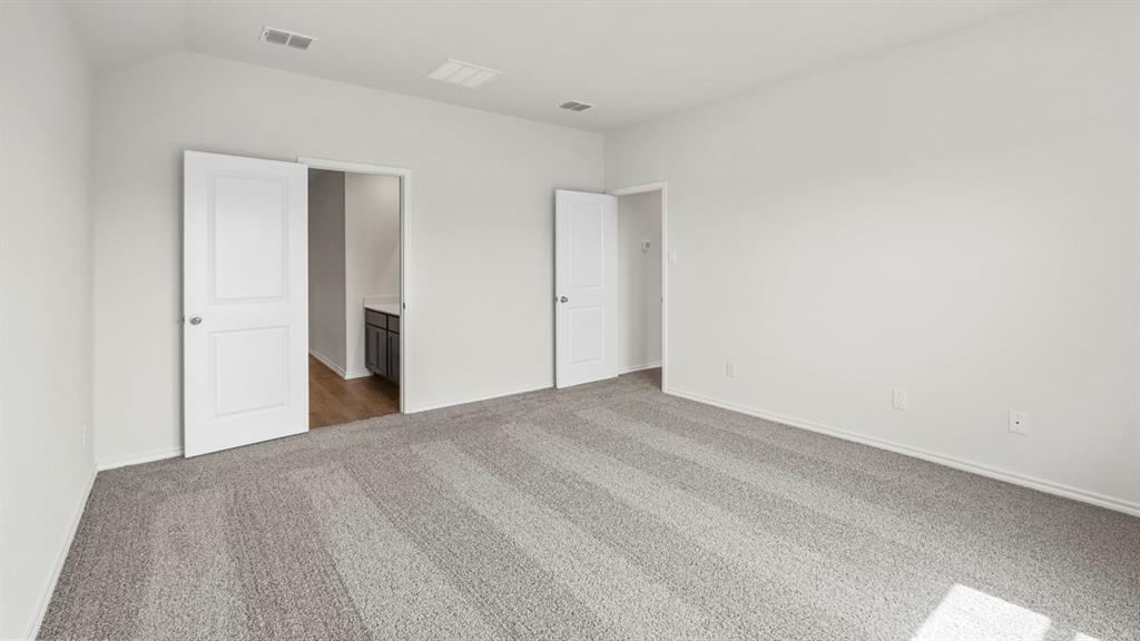 Spacious interior room featuring light gray carpeting, neutral wall tones, white trim, and white panel doors