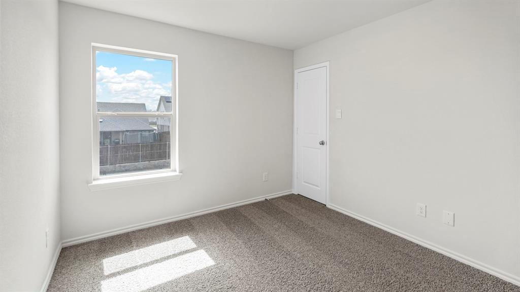 Neutral-toned room featuring a single window, white trim, light gray wall paint, and gray carpeting