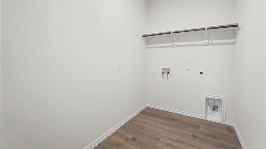 Dedicated utility space featuring a wood-finish flooring, white baseboards, and light-toned walls