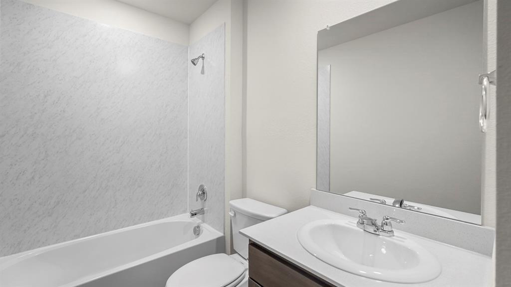 Bathroom featuring a white tub with a patterned shower surround, chrome fixtures, and a white toilet
