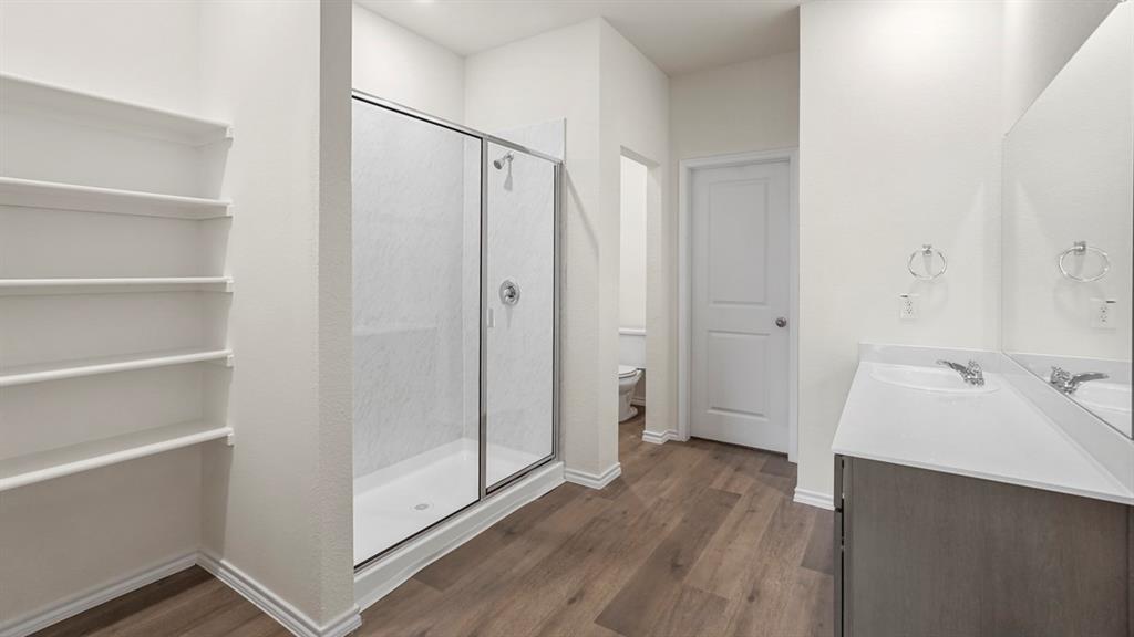 Contemporary bathroom featuring wood-finish flooring and a spacious glass-enclosed shower