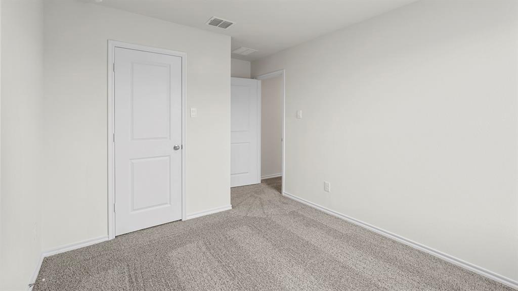 Interior room featuring light gray carpeting, white walls, white trim, and a white two-panel interior door with a brushed nickel knob