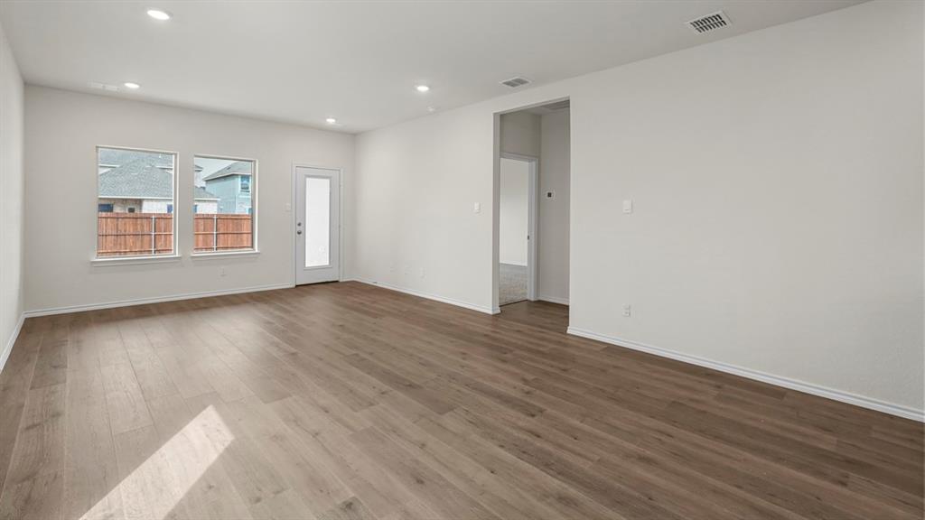Spacious room featuring wood-finish flooring, recessed lighting, and a neutral color palette