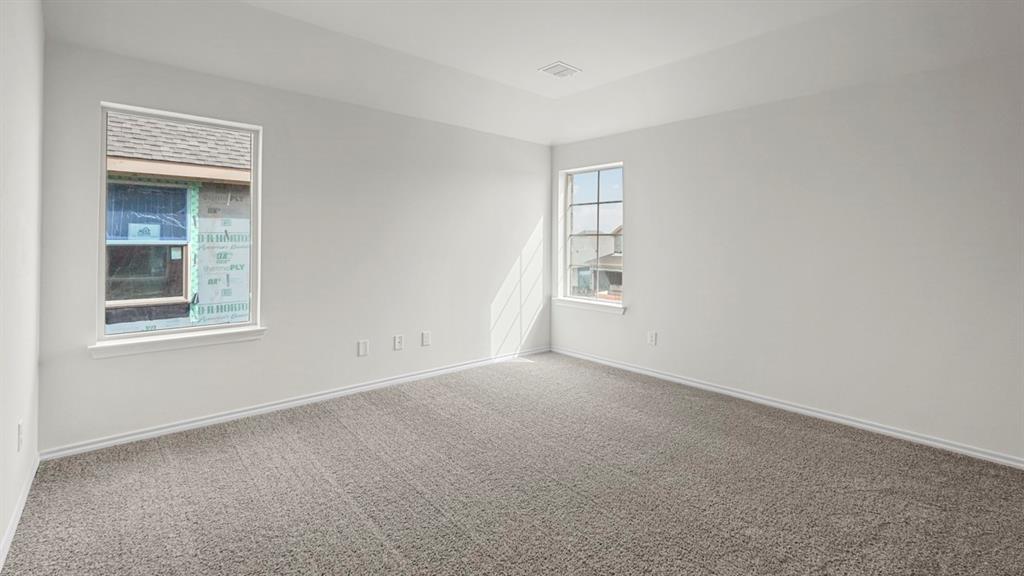 Spacious room featuring neutral grey carpeting, crisp white walls, and a recessed ceiling detail