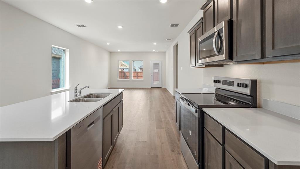 Kitchen featuring a large island with a double basin sink and stainless steel dishwasher
