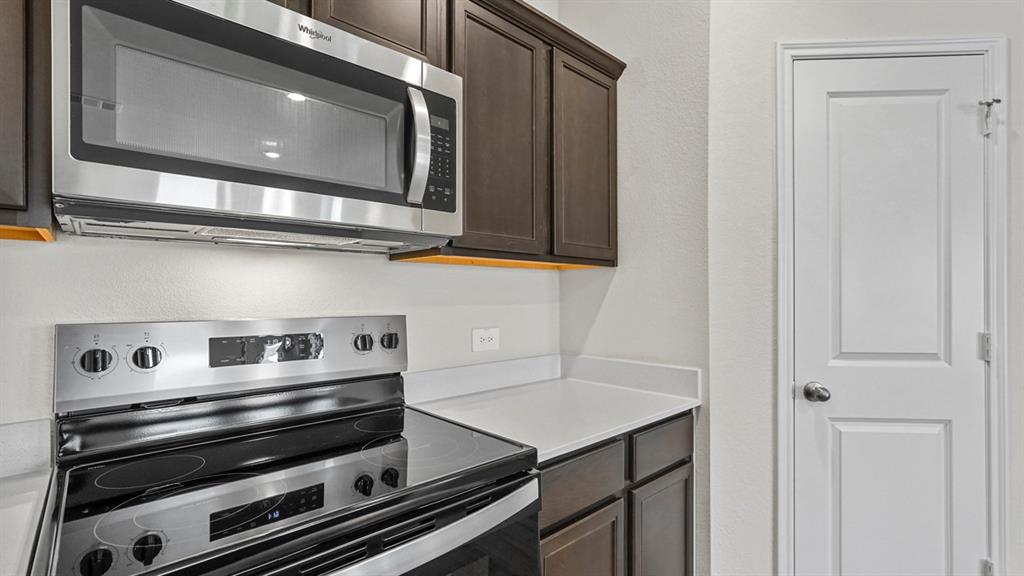 Modern kitchen featuring stainless steel appliances including a double wall oven, gas cooktop, and over-the-range microwave