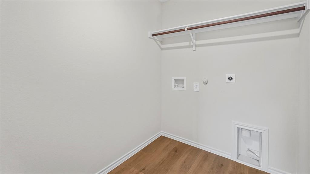 Laundry area featuring wood-finish flooring, a built-in shelf, and a clothing rod