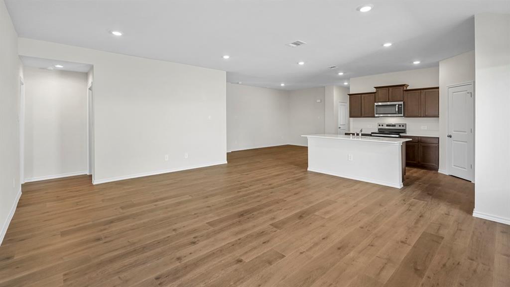 Open-concept layout with wood-finish flooring, recessed lighting, and a kitchen island featuring a breakfast bar