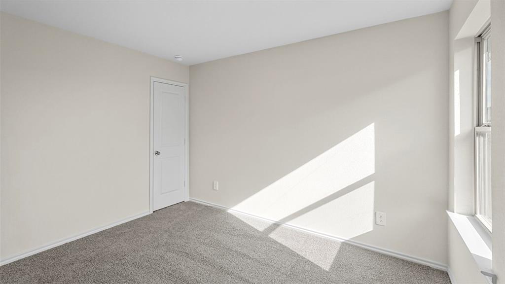 Light-colored walls, gray carpeting, recessed lighting, and a white door with a round knob