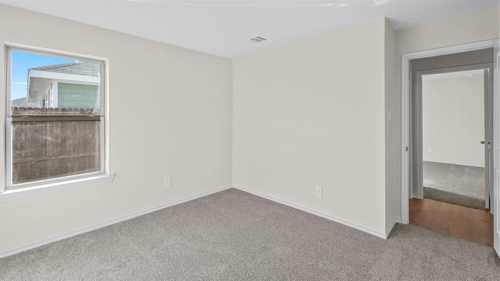 Carpeted room with a single window and neutral wall tones