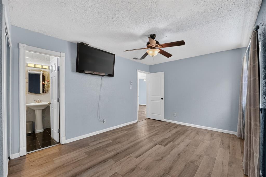 Wood-finish flooring throughout, ceiling fan with integrated lighting, and a wall-mounted television