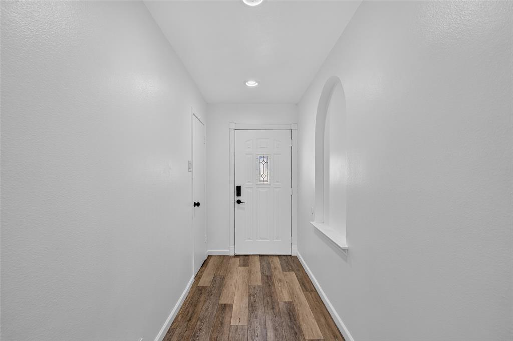Entryway featuring wood-finish flooring, recessed lighting, an arched niche, and a white paneled door with decorative glass