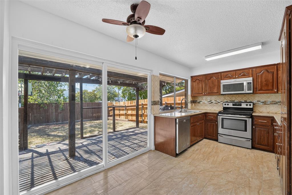 Kitchen featuring wood cabinetry, stainless steel appliances, and tile flooring