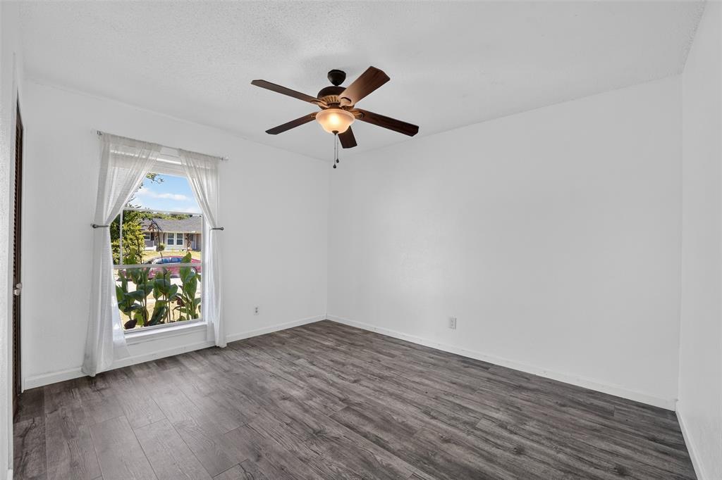 Wood-finish flooring, a window with natural light, and a ceiling fan with integrated lighting