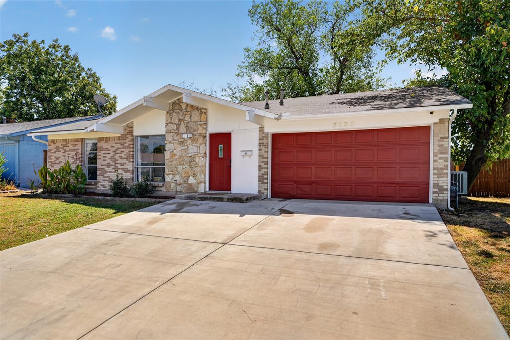 Exterior featuring brick and stone veneer, a red front door, a red garage door, and a concrete driveway Exterior featuring brick and stone veneer, a red front door, a red garage door, and a concrete driveway