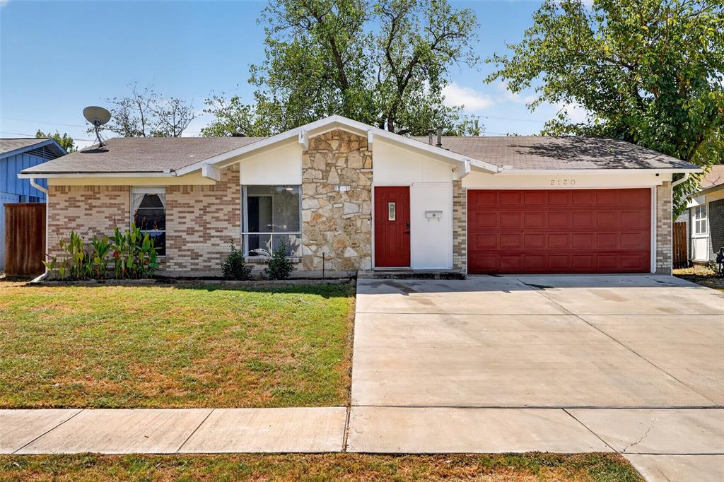 Brick and stone exterior featuring a red entry door, a red garage door, and a concrete driveway Brick and stone exterior featuring a red entry door, a red garage door, and a concrete driveway