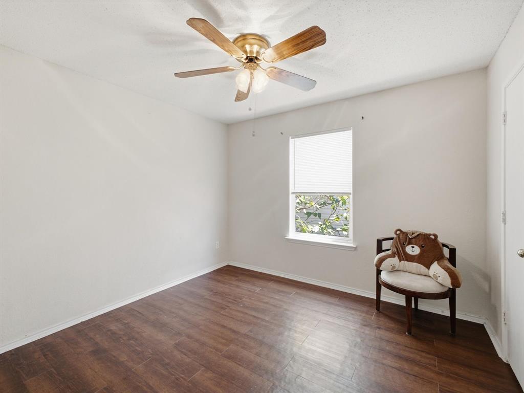Wood-finish flooring, single window with blinds, ceiling fan with integrated lighting, white walls, and a white door