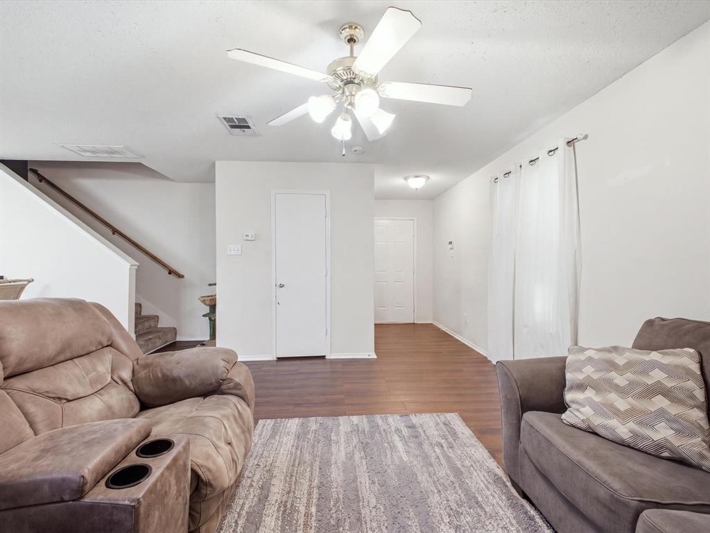 Bright interior with wood-finish flooring, a ceiling fan, and white walls