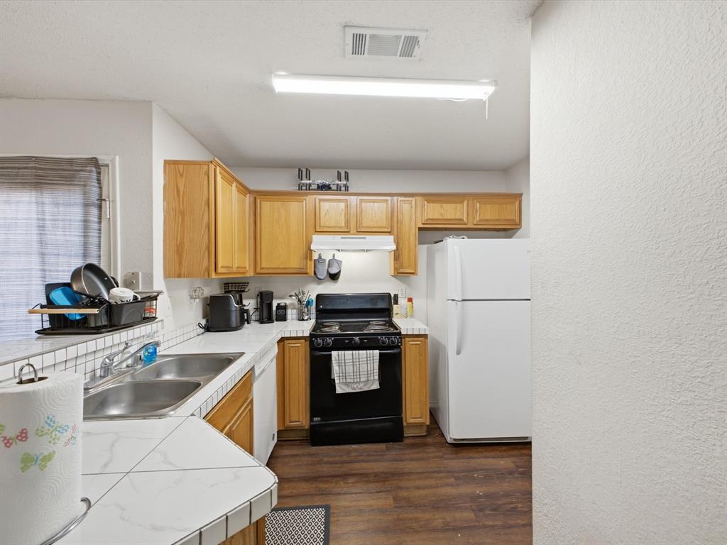 Kitchen featuring wood-finish cabinetry, tile countertops, and a dual basin stainless steel sink