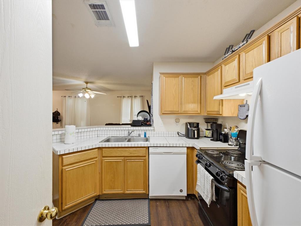 Kitchen featuring wood-finish cabinetry, white appliances, and a tile backsplash