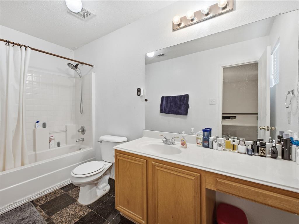 Tub and shower combination with white subway tile surround, single vanity with wood-finish cabinetry, and an integrated countertop with a single sink
