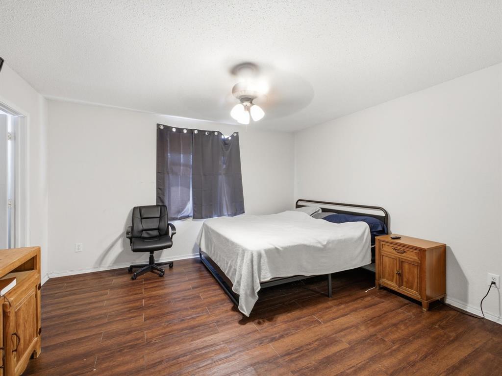 Wood-finish flooring throughout, bright white walls, and an overhead ceiling fan with lighting