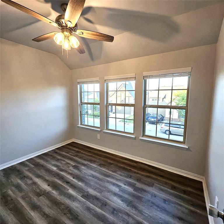 Vaulted ceiling featuring a ceiling fan with integrated lighting, wood-finish flooring, and multiple grid-pattern windows