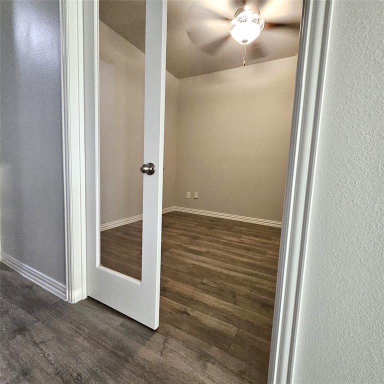 Room with wood-finish flooring, ceiling fan, and a glass-paneled entry door