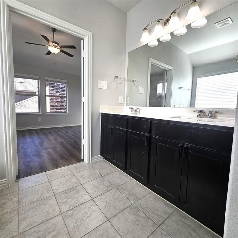 Dual vanity with black cabinetry, integrated sinks, chrome faucets, and an expansive mirror