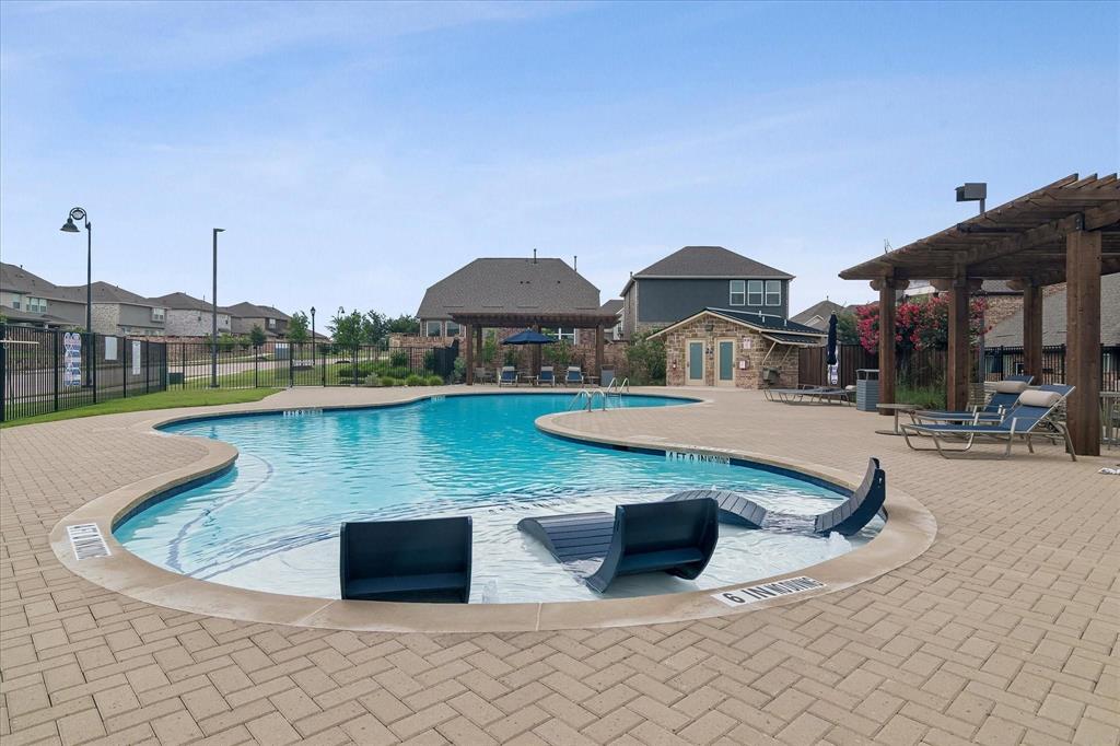 Resort-style swimming pool featuring an irregular shape, a sun shelf, and integrated lounge seating
