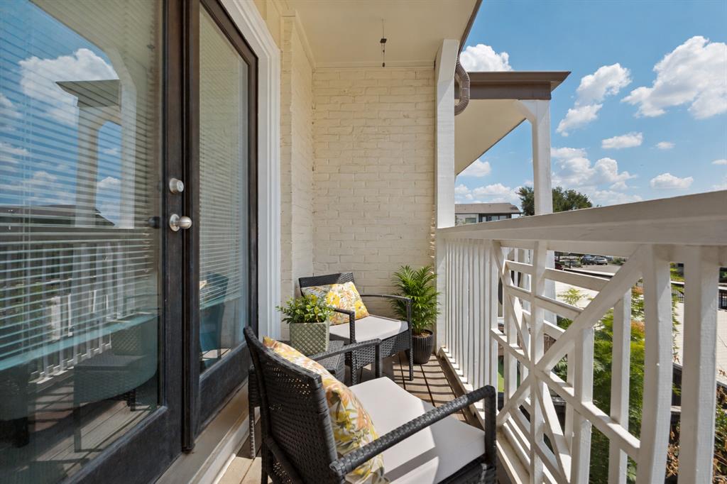 Private balcony with a painted brick exterior, white balusters, and a decorative railing panel