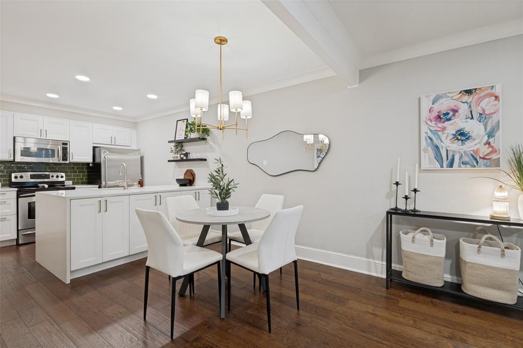 Kitchen and dining area featuring wood-finish flooring, white cabinetry, stainless steel appliances, and a green tile backsplash