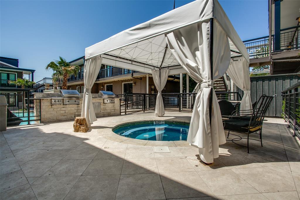 Paved patio with an in-ground spa, a freestanding gazebo, and a built-in outdoor kitchen featuring two stainless steel grills