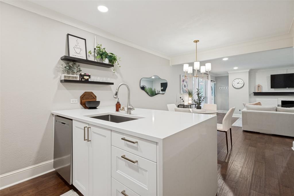 Kitchen island with white cabinetry, stainless steel dishwasher, and an undermount sink with a gooseneck faucet