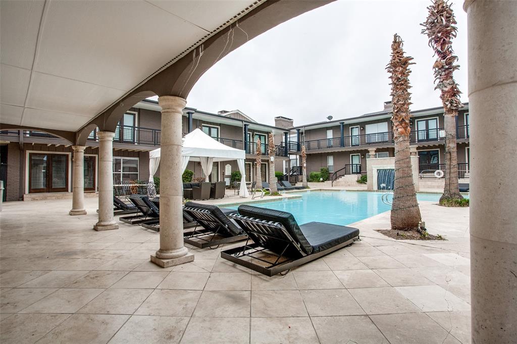 Expansive pool deck with tiled surfacing, arched covered patio, and column supports
