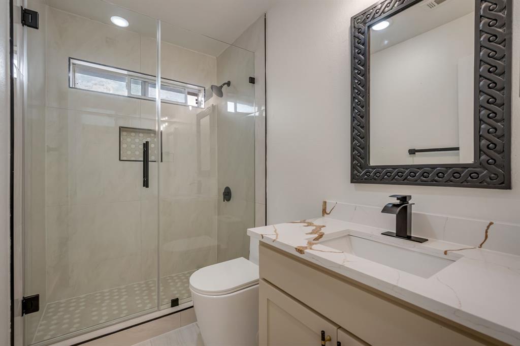 Walk-in shower with clear glass enclosure, transom window, and tiled accent niche