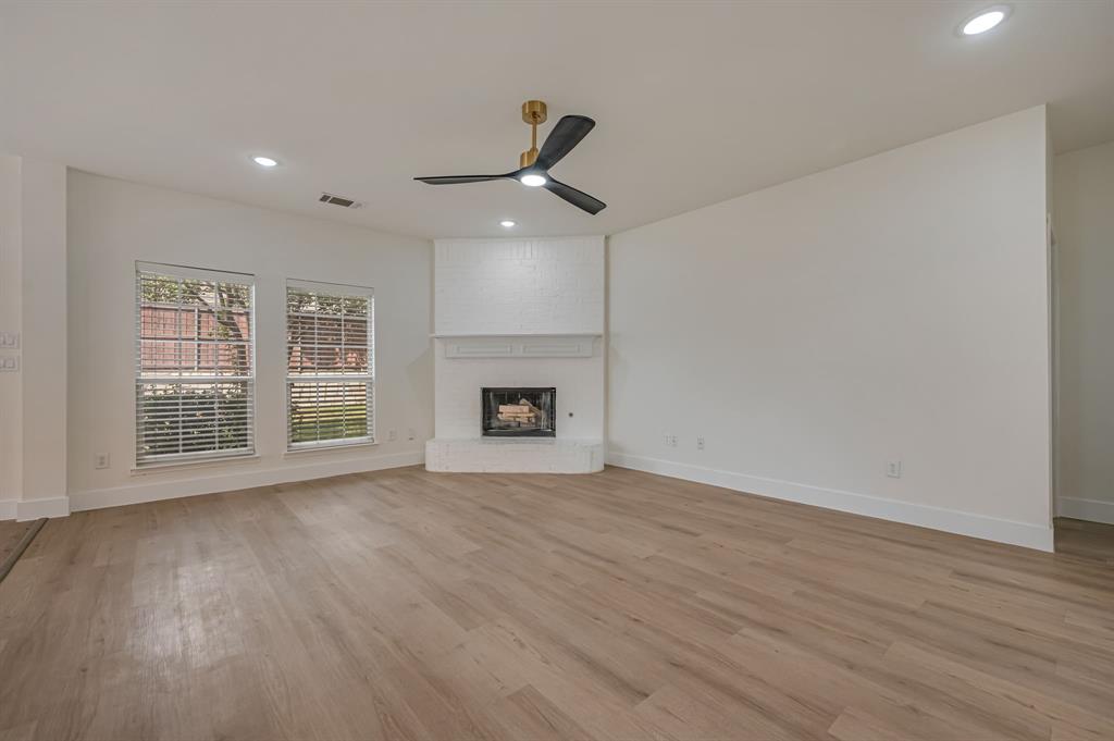 Luxury Vinyl Plank  flooring, brick fireplace with mantel, recessed lighting, ceiling fan, and multiple windows