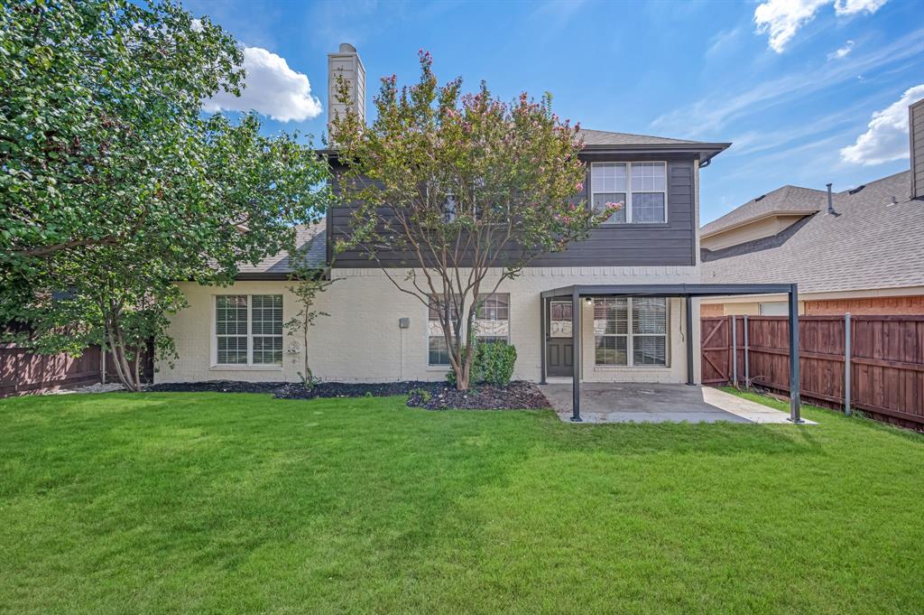 Expansive lawn, covered patio, wood privacy fencing, and mature trees complement the exterior