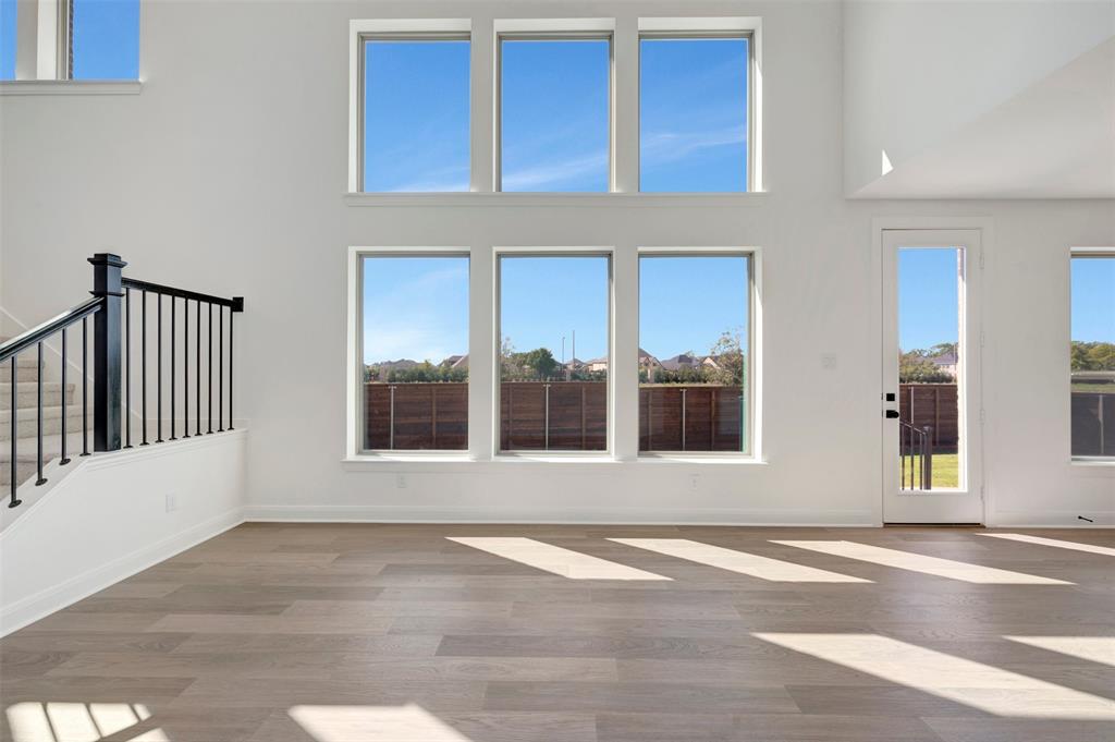 Two-story living area with high ceilings, wood-finish flooring, and multiple windows