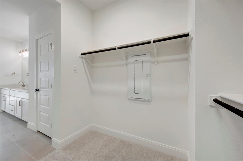 Built-in closet shelving and hanging rod with light-toned carpeting